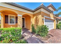 Inviting front entrance with arched doorway, shutters, and well-maintained landscaping at 10072 Cozy Grove Dr, Venice, FL 34293