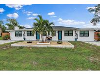Charming home with white stucco, black trim and bright blue doors and decorative stone garden at 11 1St E St, Nokomis, FL 34275
