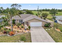 Charming home with two car garage, a pristine driveway, and manicured garden beds at 125 Golf Club Ln, Venice, FL 34293