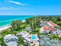 Stunning aerial view of beachfront property with pool, tennis courts, and lush landscaping near the ocean at 5055 Gulf Of Mexico Dr # 115, Longboat Key, FL 34228