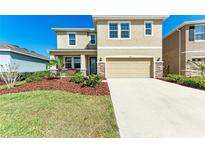Two-story home with tan exterior, stone accents, well-maintained landscaping, and a two-car garage at 5336 Grove Mill Loop, Lakewood Ranch, FL 34211