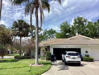 Charming single-story home featuring a well-manicured lawn, mature landscaping, and a white car parked in the driveway at 5714 Garden Lakes Dr, Bradenton, FL 34203