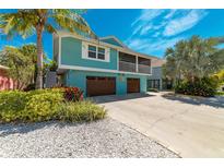 Charming two-story teal home with a screened-in porch, mature landscaping, and a two-car garage at 805 N Bay Blvd, Anna Maria, FL 34216