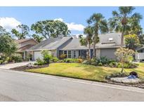 Charming single-story home with a stone accent wall, lush landscaping, and mature palm trees adding curb appeal at 811 Hammockwood Ct, Sarasota, FL 34232