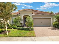 Charming single-story home with lush landscaping, brick driveway, and a beautiful terracotta tile roof at 11499 Renaissance Blvd, Venice, FL 34293
