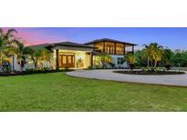 Stunning two-story home with a circular driveway, lush lawn, and tropical landscaping at 1208 Oak Hammock Rd, Sarasota, FL 34240