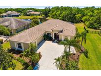 Stunning aerial view of a house with a tile roof, lush landscaping, and a spacious driveway at 12810 Kite Dr, Bradenton, FL 34212