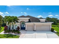 Stunning home featuring a three-car garage, beautiful landscaping, and a welcoming front entrance with palm trees at 12841 Balsam Ter, Bradenton, FL 34212