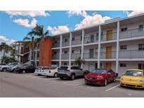 White condo building featuring orange accent with ample parking and tropical landscaping on a sunny day at 2340 Canal Dr # G-35, Bradenton, FL 34207