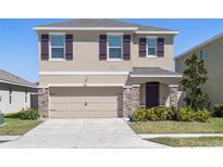 Two-story home with a two-car garage, neutral paint, stone accents, manicured landscaping and purple shutters at 5868 Calla Lilly Dr, Sarasota, FL 34232