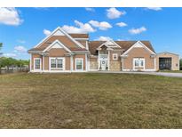 Stunning brown two-story home with stone accents, white trim, large windows, and manicured lawn on a beautiful day at 5949 225Th E St, Bradenton, FL 34211