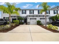 Charming townhome with a two-car garage, palm trees, and beautifully landscaped front yard at 6473 Baytown Dr, Sarasota, FL 34240
