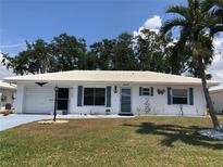 Charming single-story home featuring a white exterior, white tile roof, blue shutters, and a well-manicured lawn at 1007 Pussywillow Ln, Bradenton, FL 34208