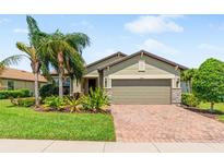 Charming single-story home with well-manicured lawn, lush landscaping, and a brick-paved driveway at 11214 Sandhill Preserve Dr, Sarasota, FL 34238