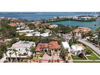 An aerial view of a luxurious waterfront home surrounded by lush tropical landscaping with a beautiful red tile roof at 113 Fillmore Dr, Sarasota, FL 34236