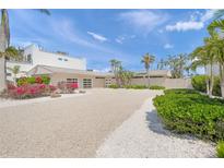 Contemporary home featuring a gravel driveway and beautiful landscaping, complemented by palm trees and vibrant bougainvillea at 1186 Center Pl, Sarasota, FL 34236