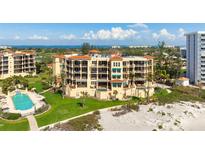 Beautiful beachfront resort with a pool, manicured lawn and tropical landscaping on a sunny day at 2333 Gulf Of Mexico Dr # 1A2, Longboat Key, FL 34228
