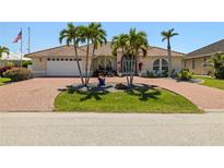 Charming home with brick driveway, palm trees, tile roof, and lush landscaping creates appealing curb appeal at 2817 La Mancha Ct, Punta Gorda, FL 33950