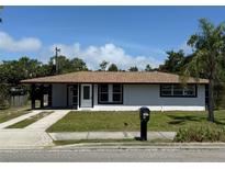 Charming single-story home featuring a well-manicured lawn, covered carport, and freshly painted exterior at 2919 Bayshore Gardens Pkwy, Bradenton, FL 34207