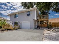 Two-story home featuring a wooden deck, light gray siding, garage, and concrete driveway at 3356 Maiden Ln, Sarasota, FL 34231