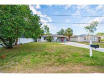 Charming single-story home features a well-manicured lawn and a classic red front door, exuding warmth at 3515 W Pearl Ave, Tampa, FL 33611