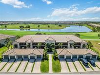Stunning aerial view of condo building overlooking the golf course and lake with palm tree-lined entrance at 5664 Palmer Cir # 102, Bradenton, FL 34211