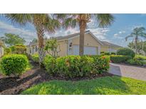 Charming single-Gathering home with a two-car garage, lush landscaping, and beautiful mature palm trees at 5934 Guarino Dr, Sarasota, FL 34238