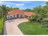 Beautiful single-story home featuring a brick driveway, well-manicured lawn, and a lush tropical landscape at 6390 Yellow Wood Pl, Sarasota, FL 34241