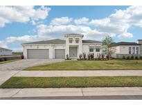 Charming single-story home features a manicured lawn, three-car garage, and bright white exterior at 8405 Golden Beach Ct, Parrish, FL 34219