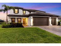 Charming two-story home with a lush green lawn and a three car garage at 11435 Apple Tree Cir, Bradenton, FL 34211