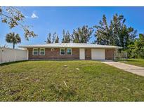 Charming single-story brick home with a well-manicured lawn and a freshly painted white metal roof at 12305 Harland St, North Port, FL 34287