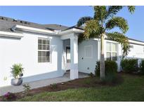 Inviting home exterior featuring a light blue facade, manicured lawn, and a lovely tropical palm tree at 17817 Woodland Ct, Punta Gorda, FL 33982