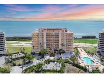 Stunning waterfront condo building with a pool, parking and landscaped grounds against a beautiful sky at 3030 Grand Bay Blvd # 323, Longboat Key, FL 34228