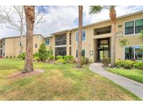 Tan condo building featuring tropical landscaping, screened patios, and well-maintained grassy areas at 4017 Crockers Lake Blvd # 1421, Sarasota, FL 34238