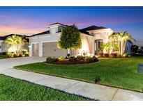 Stunning home with a well-manicured lawn and lush landscaping, illuminated by warm exterior lighting at dusk at 4625 Foxtail Dr, Parrish, FL 34219