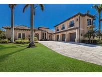 Stunning exterior showcasing a paver driveway, lush lawn, and a grand entrance, all nestled amidst swaying palm trees at 4711 17Th W St, Palmetto, FL 34221