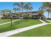 Attractive condo building with lush landscaping, sidewalk, and mature palm trees on a sunny day at 6500 Flotilla Dr # 125, Holmes Beach, FL 34217