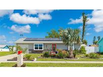 Charming single-story home features a vibrant red door, solar panels, and a beautifully landscaped front yard at 13492 Dibella Ave, Port Charlotte, FL 33981