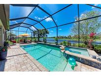 Sparkling pool and spa area with a screened enclosure and serene lake view, perfect for outdoor relaxation and entertaining at 19921 Petrino St, Venice, FL 34293