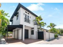 Stunning modern two-story home featuring a white exterior, black trim, and lush tropical landscaping at 324 Siesta Dr, Sarasota, FL 34242