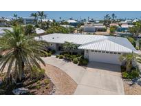 Beautiful home featuring lush landscaping, a pristine white roof, and an attached two-car garage at 606 Emerald Ln, Holmes Beach, FL 34217