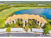Stunning aerial view of the condo with golf course, lake, and parking; beautiful grounds with lush tropical landscaping at 7705 Grand Estuary Trl # 202, Bradenton, FL 34212