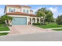 Charming two-story home featuring a brick driveway, a teal garage door, and a well-manicured lawn at 13721 Saw Palm Creek Trl, Lakewood Ranch, FL 34211