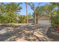 Charming home featuring a brick driveway and a well-manicured yard with mature trees and lush landscaping at 2072 Misty Sunrise Trl, Sarasota, FL 34240