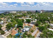 An aerial view of a charming neighborhood showcases a cozy home with a pool, surrounded by lush greenery and city views at 2120 8Th W Ave, Bradenton, FL 34205