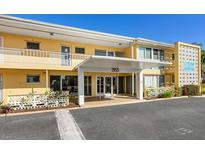 The front of a two-story yellow building with a covered entrance at 2155, under a clear blue sky at 2155 Wood St # B18, Sarasota, FL 34237