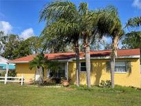 Charming home featuring vibrant yellow exterior, lush palm trees, well-maintained lawn, and red roof at 3612 27Th W Ave, Bradenton, FL 34205