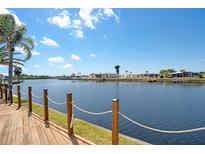 Scenic waterfront view from a wooden deck, showcasing the tranquil canal and neighboring homes under a clear sky at 520 Ideal Pl, North Port, FL 34287