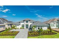 Beautiful home with a grey brick driveway, tropical landscaping, and grey shingled roof at 600 Blue Shell Loop, Sarasota, FL 34240
