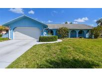 Charming blue single-story home featuring a well-manicured lawn and an attached two-car garage at 6004 10Th Ave W, Bradenton, FL 34209